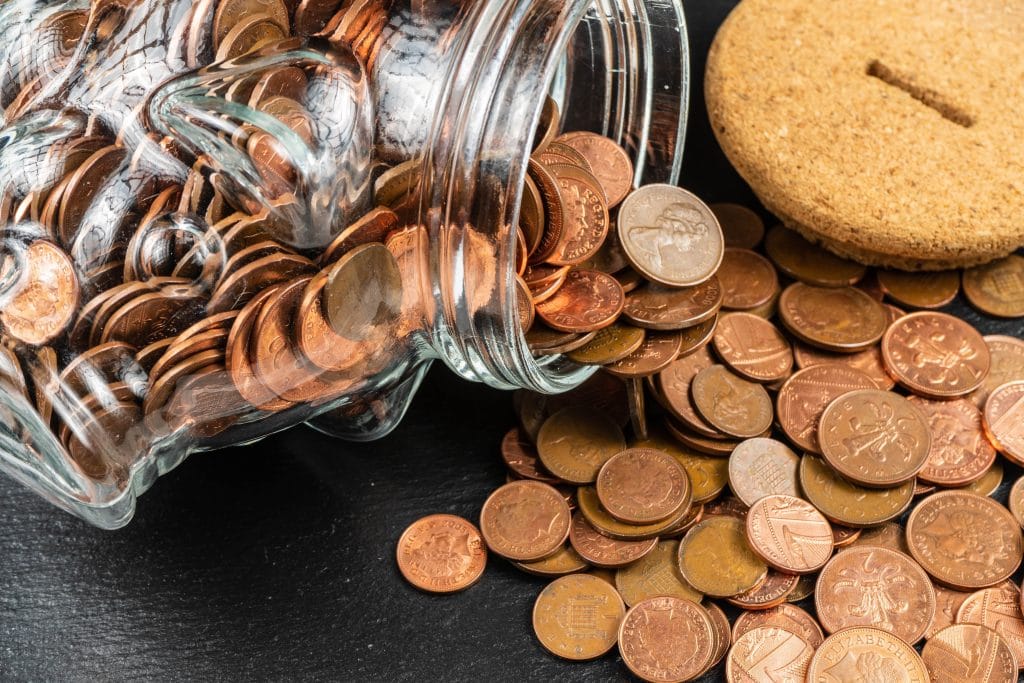 Münzen neben einem umgekippten Glas als Symbol für Finanzierung